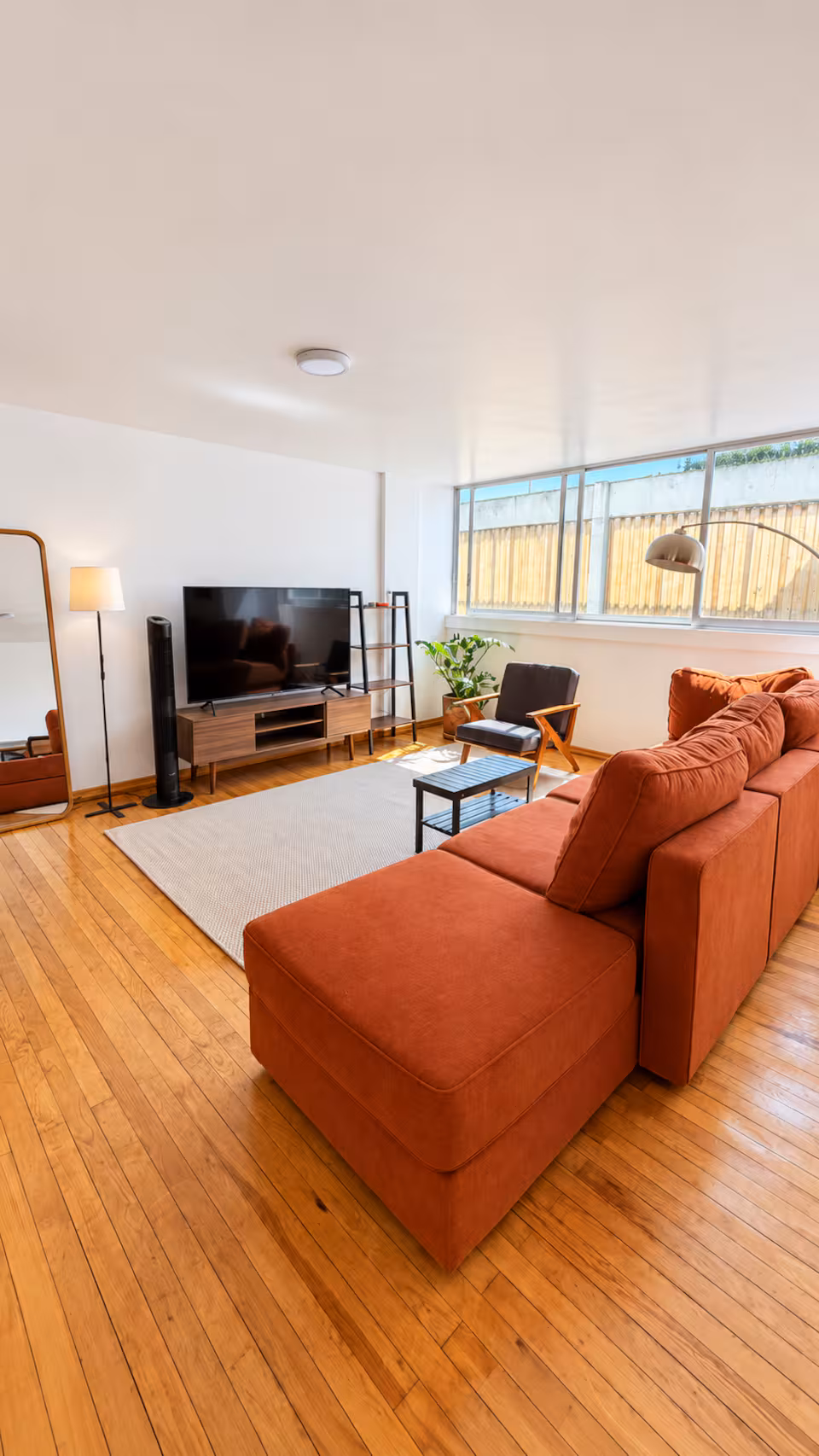 The living room at Casa Colima, with wood floors, a terracotta sofa and large windows